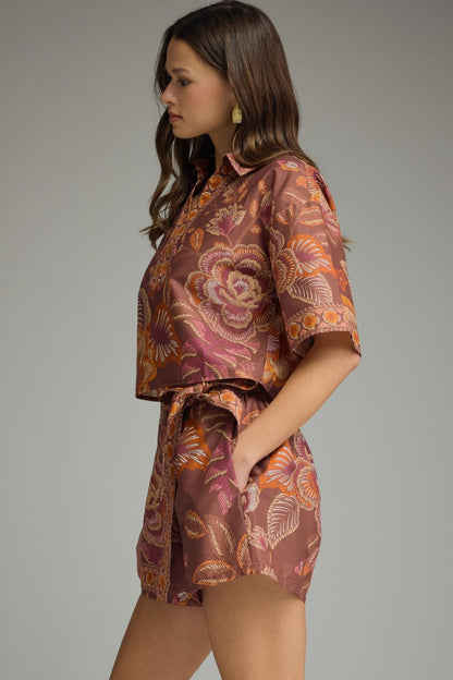 Side view of terracotta floral matching set featuring short sleeve cropped top and tie-waist skort in orange and pink floral print.