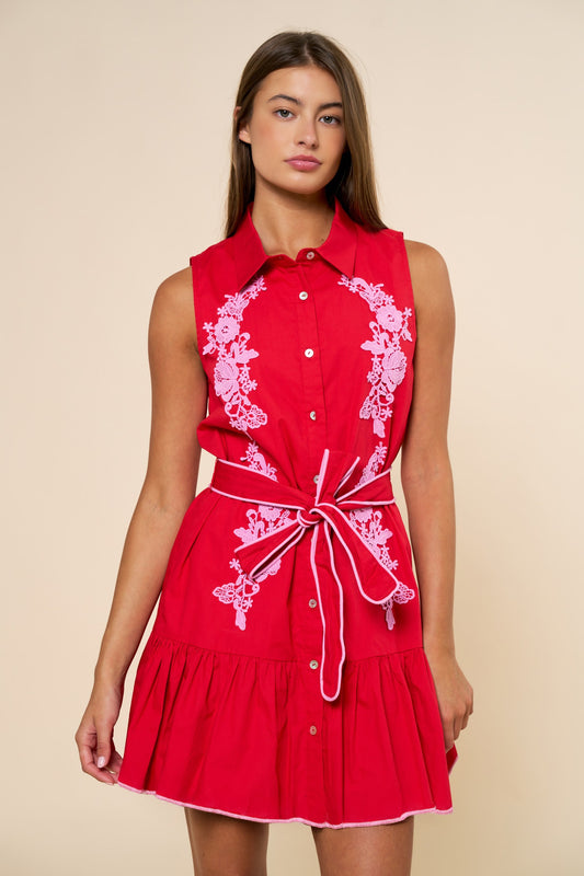 vibrant red sleeveless mini dress with blush floral embroidery, button front detail, tie waist belt, and ruffle hem.