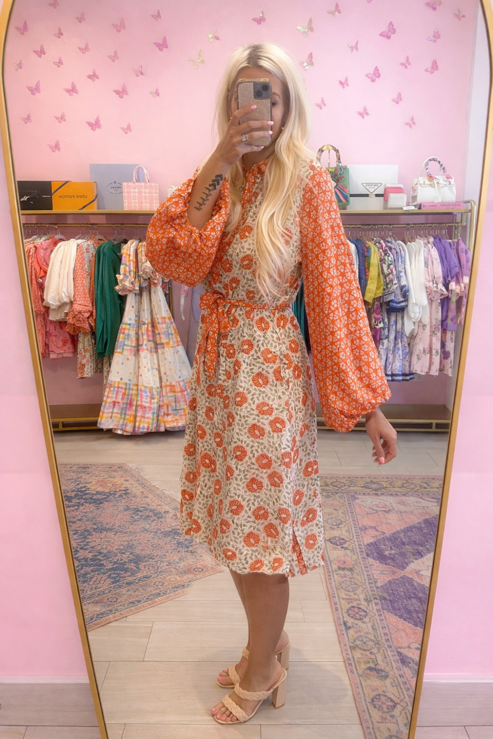 Person wearing a floral dress with orange accents in a store setting.