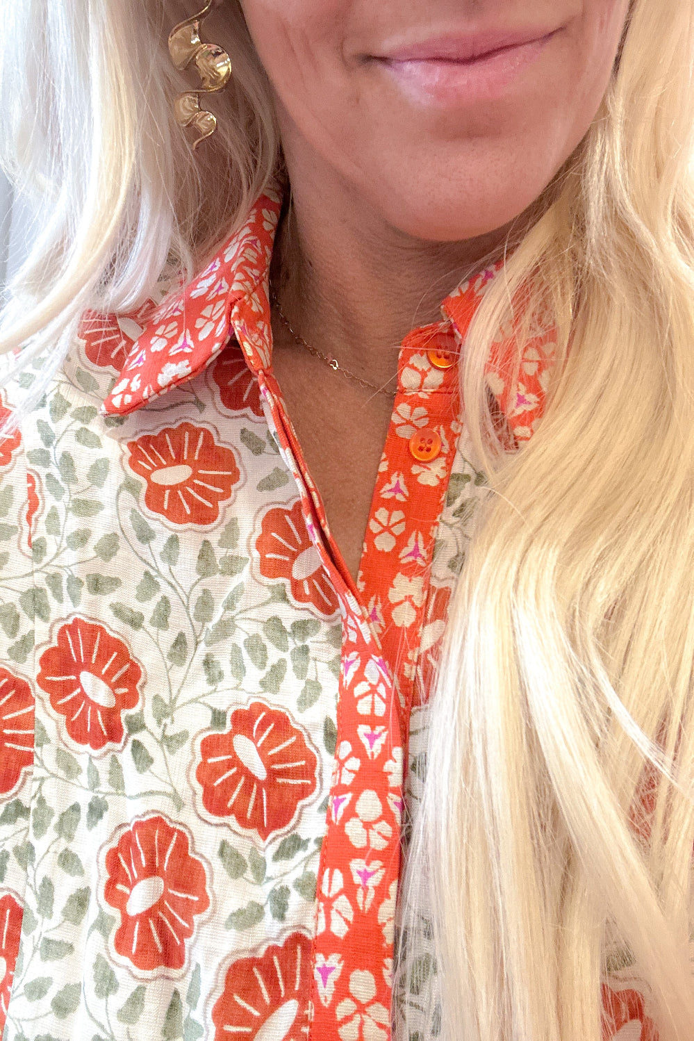Close-up of a person wearing a floral patterned shirt with orange and green colors.