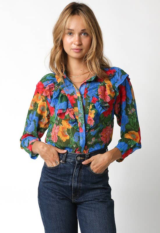 Woman wearing a colorful floral blouse and jeans on a white background