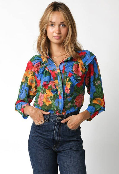 Woman wearing a colorful floral blouse and jeans on a white background