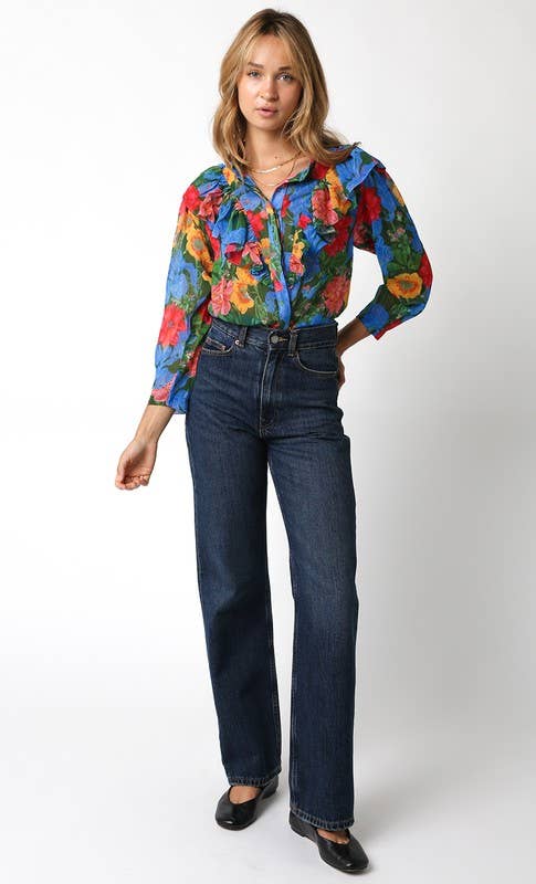 Woman wearing a colorful floral blouse and blue jeans on a white background