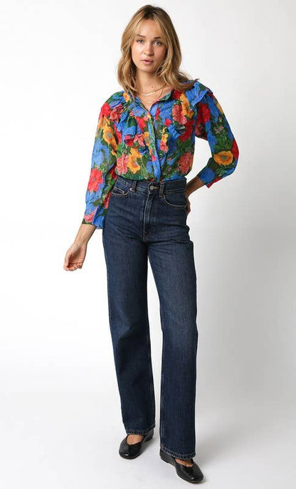 Woman wearing a colorful floral blouse and blue jeans on a white background