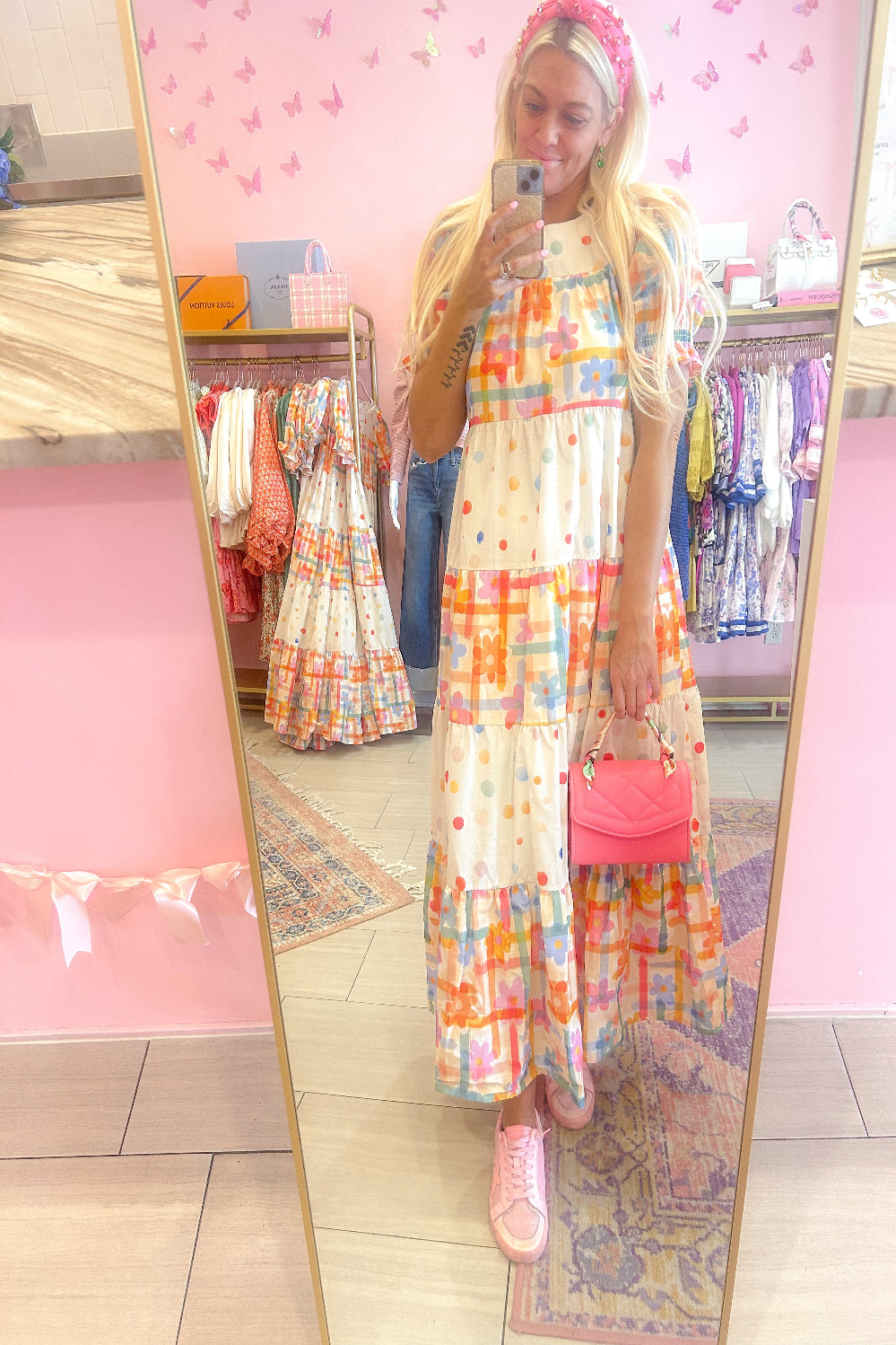 Person wearing a colorful dress in a store with pink walls and clothing racks.