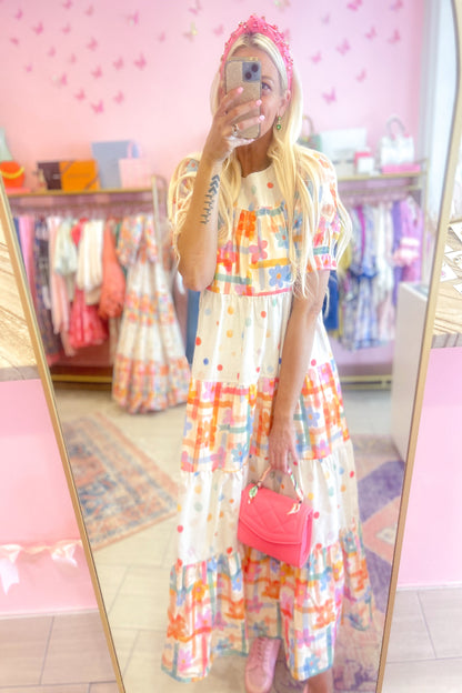 Person wearing a colorful dress with a pink bag in a store setting.