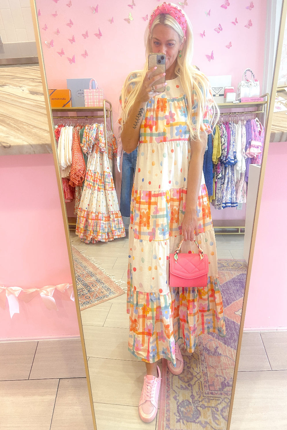 Person wearing a colorful dress in a store with pink walls and clothing racks.
