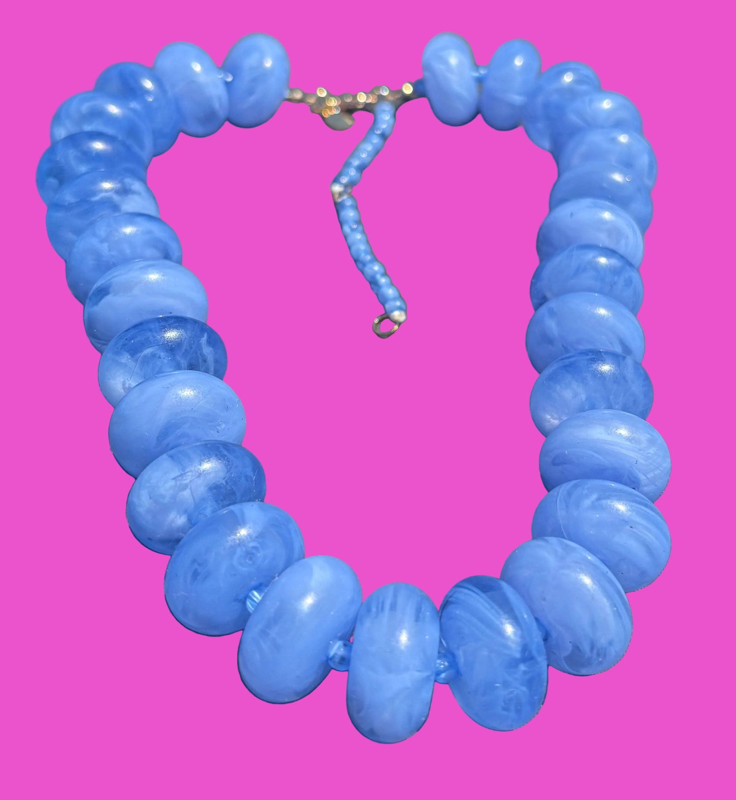 Blue beaded necklace on a pink background