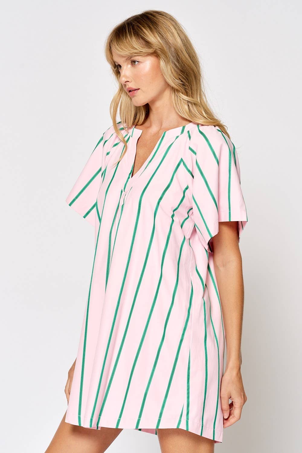 Woman wearing a pink and green striped dress on a white background
