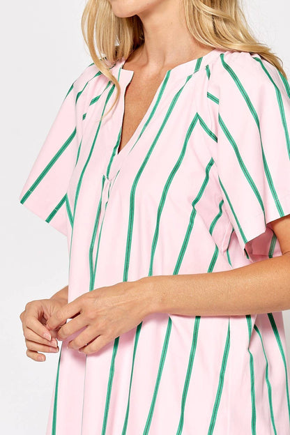 Pink and green striped dress worn by a person on a white background