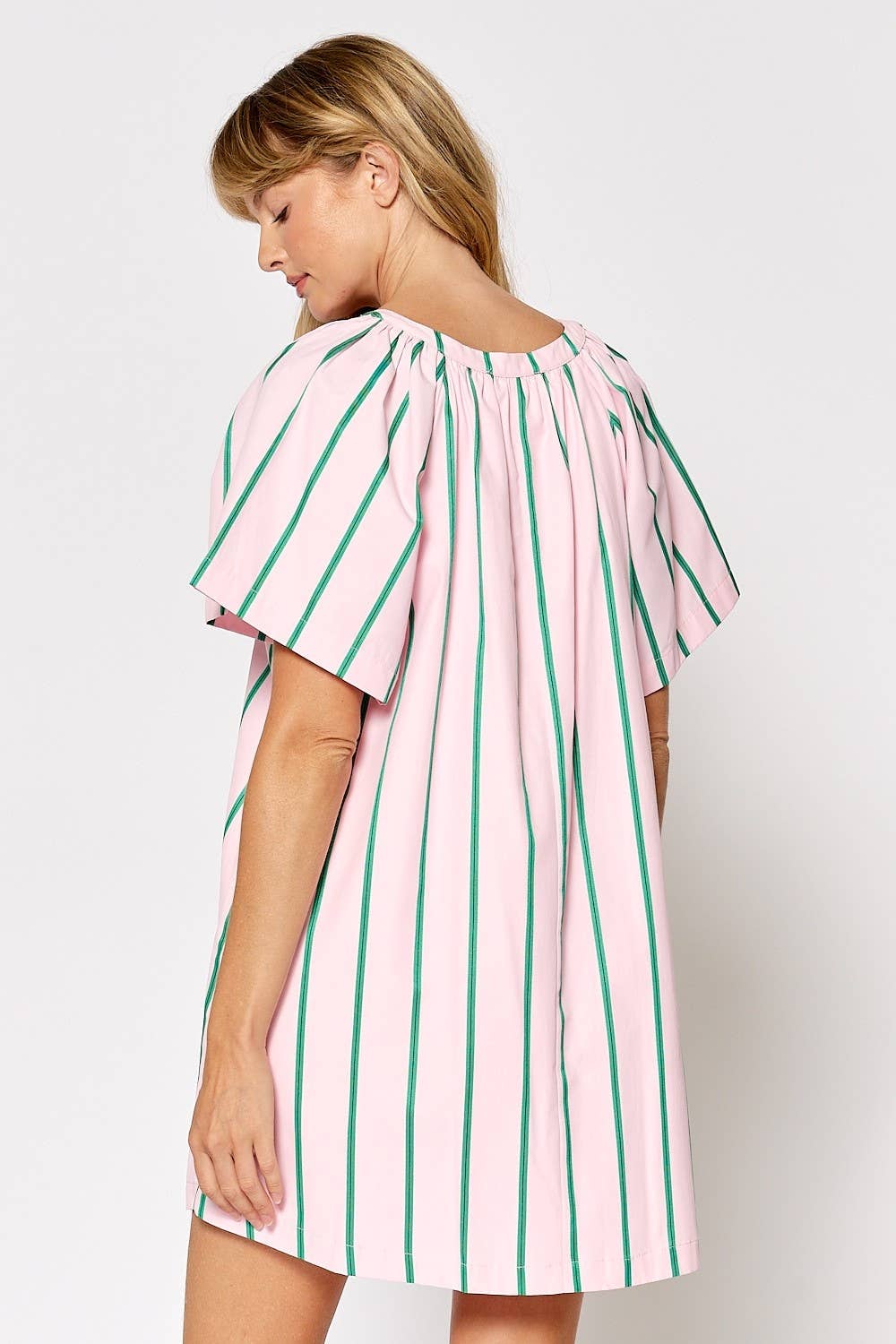 Woman wearing a pink and green striped dress on a white background
