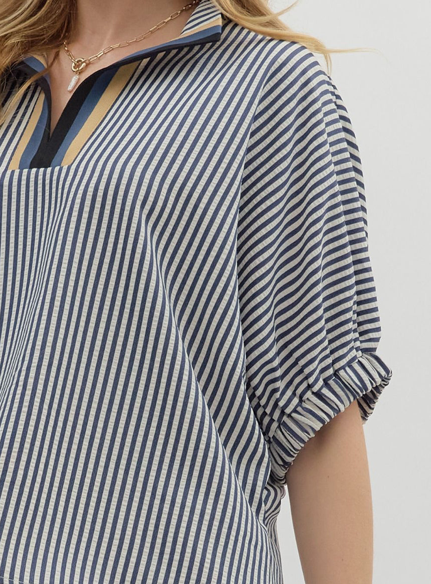 Close-up of a person wearing a blue and white striped shirt with a neutral background