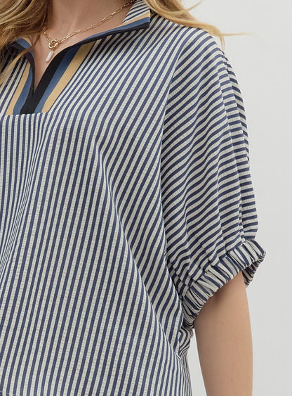 Close-up of a person wearing a blue and white striped shirt with a neutral background