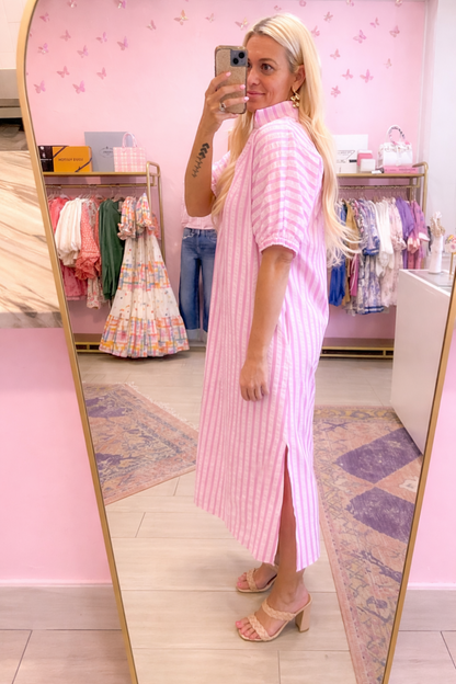 Woman in a pink dress standing in front of a mirror in a store.