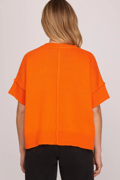 Person wearing an orange sweater on a plain background