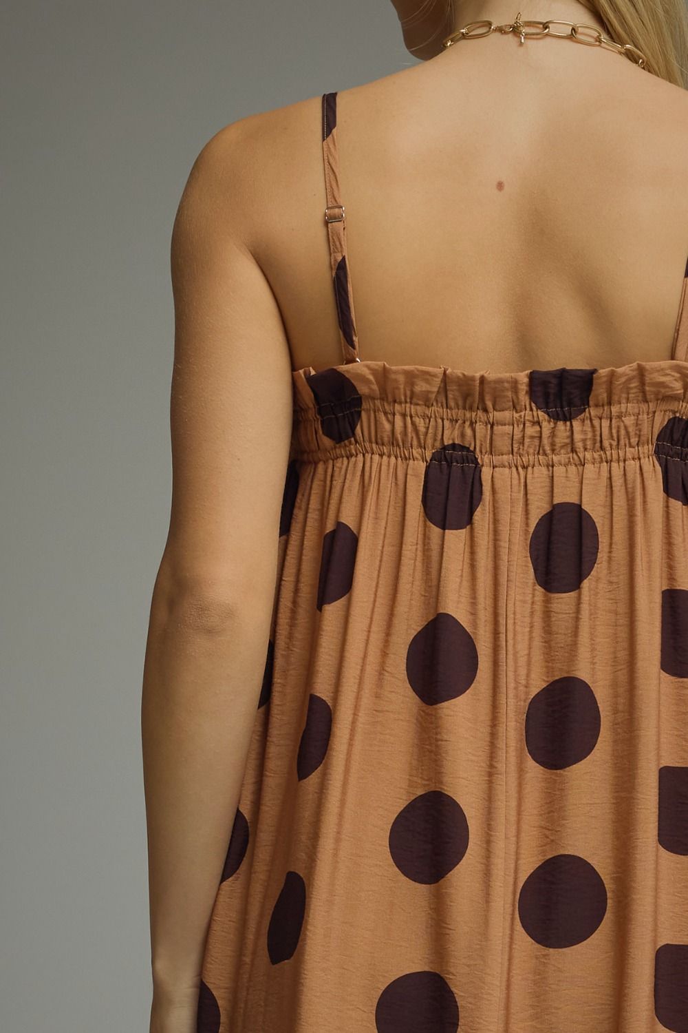 Brown dress with black polka dots worn by a person on a gray background