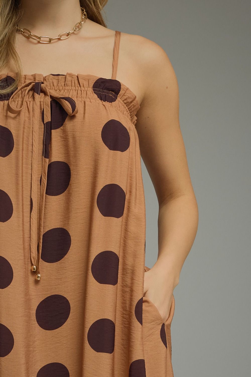 Brown dress with large polka dots worn by a person on a gray background