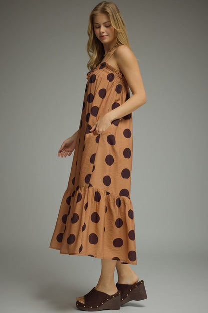 Woman wearing a brown dress with black polka dots against a gray background