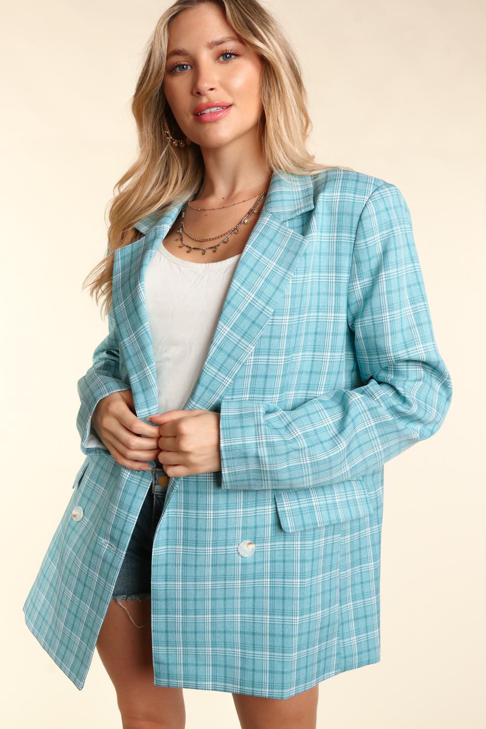 Woman wearing a turquoise plaid oversized blazer with a classic lapel collar, white button details, and cuffed sleeves.
