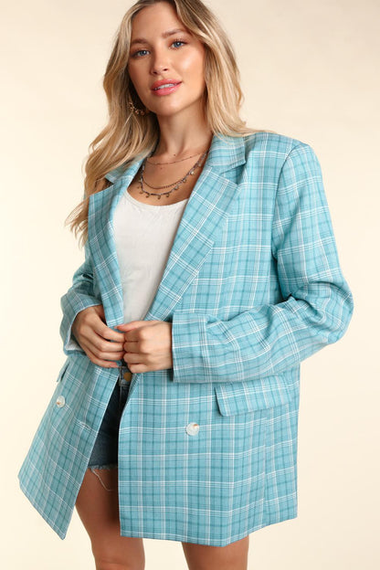 Woman wearing a turquoise plaid oversized blazer with a classic lapel collar, white button details, and cuffed sleeves.