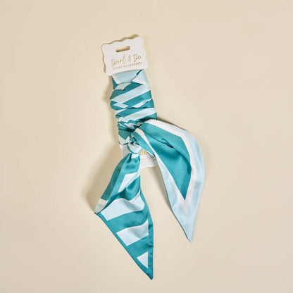 Teal and white patterned hair scarf on a beige background