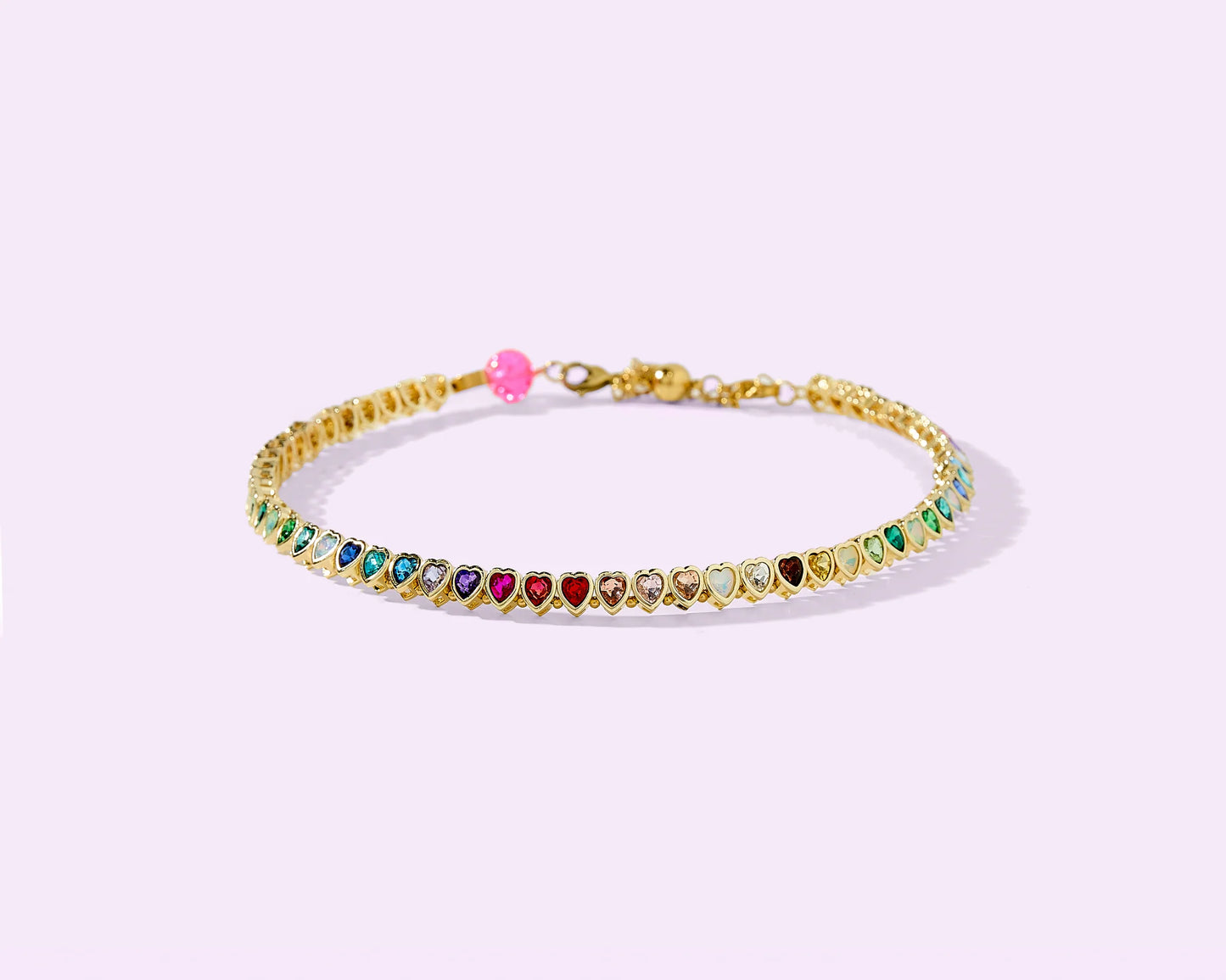 Gold bracelet with multicolor heart-shaped gemstones on pastel background