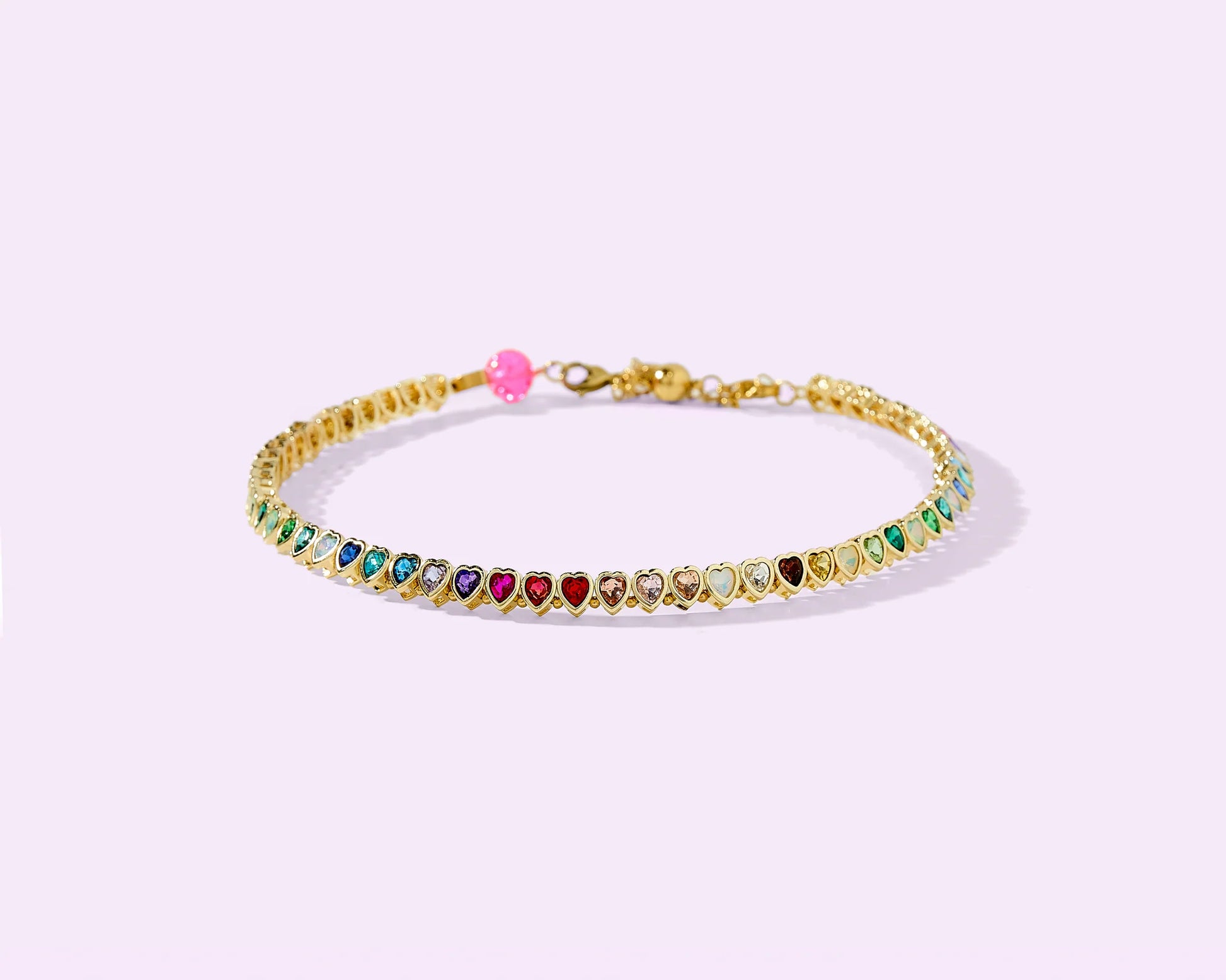 Gold bracelet with multicolor heart-shaped gemstones on pastel background