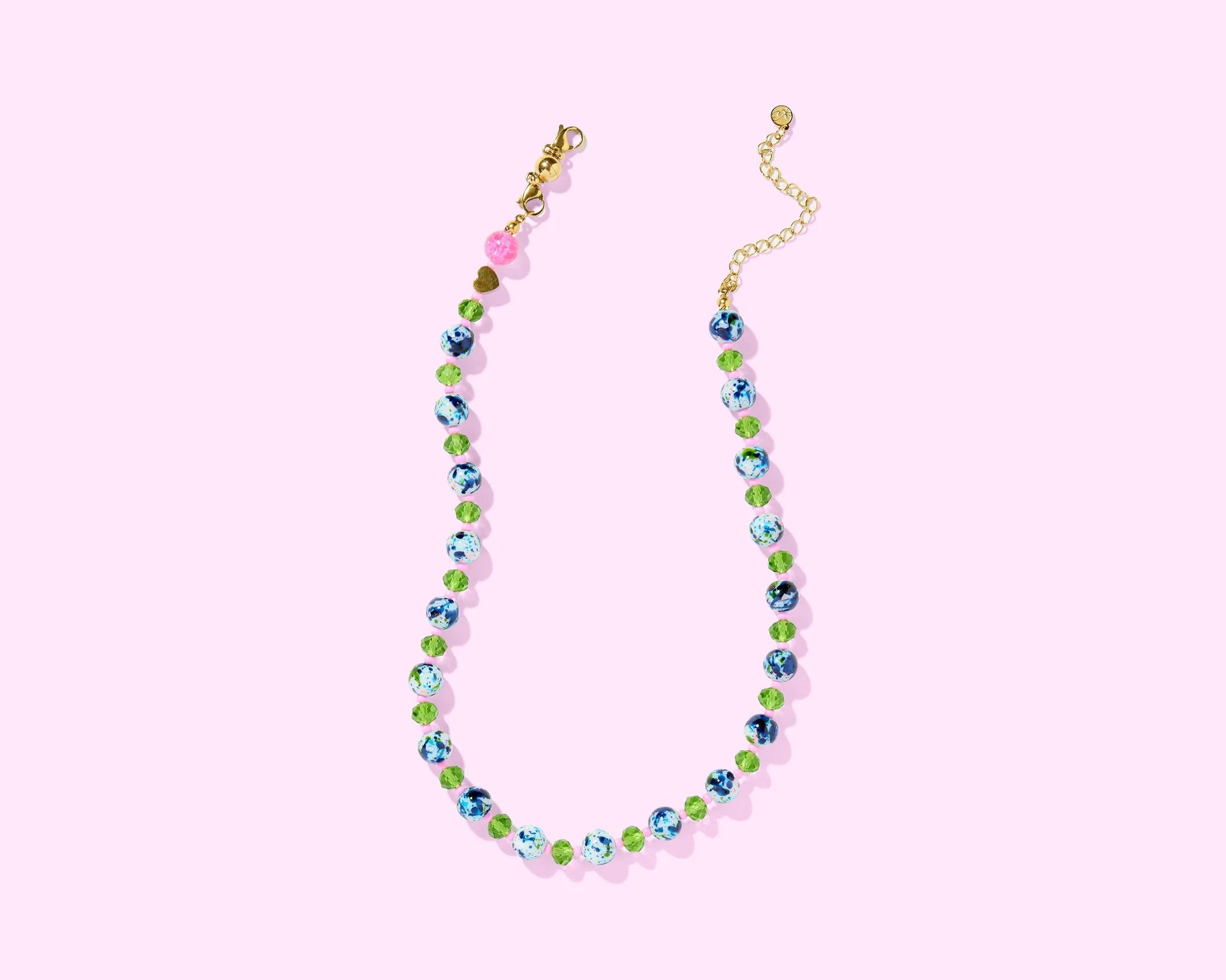 Colorful beaded necklace with blue, green, and pink beads on a pastel pink background