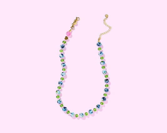 Colorful beaded necklace with blue, green, and pink beads on a pastel pink background