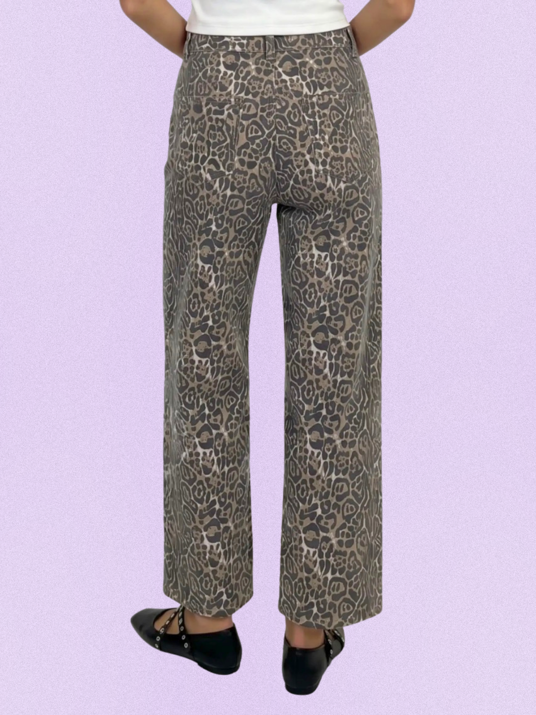 A person shown from the waist down wearing leopard-print pants in beige, brown, and gray tones, paired with a white top and black flats, against a solid lavender background.
