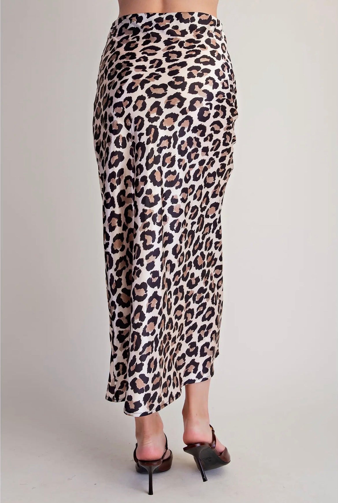 A leopard print midi skirt with a beige, brown, and black pattern, shown on a model from the back against a light gray studio background.
