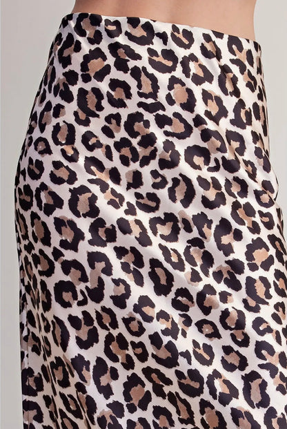 Close-up of a leopard print skirt with a cream base and black, brown, and beige spots, shown on a model.