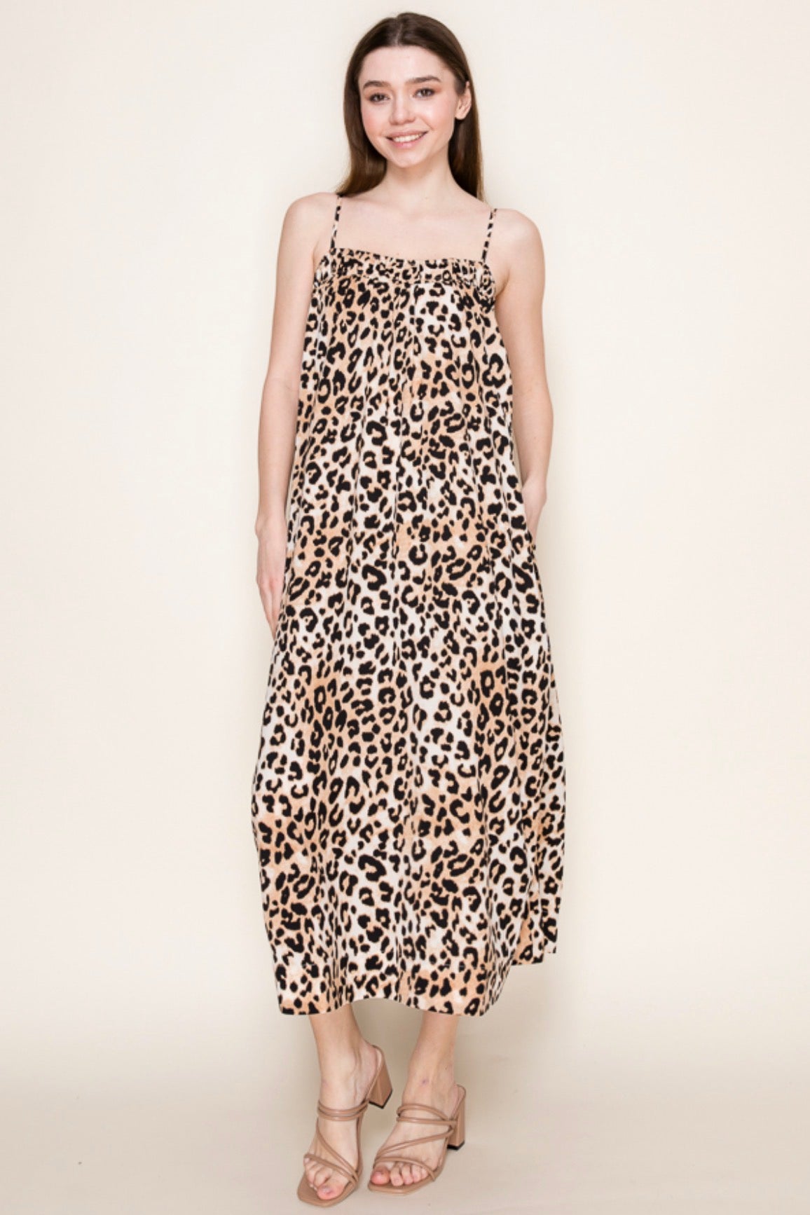 Woman wearing a leopard print dress on a plain background