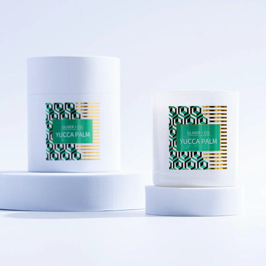 Two white cylindrical containers of Yucca Palm candle wax by Blumer & Co, displayed on matching white pedestals against a clean white background.