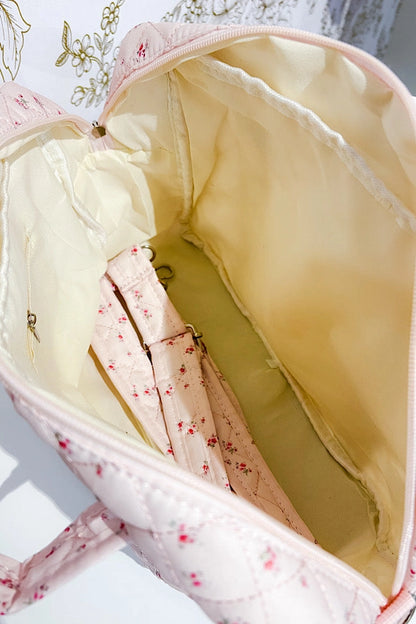 Interior of a light pink floral quilted handbag with cream lining and pockets