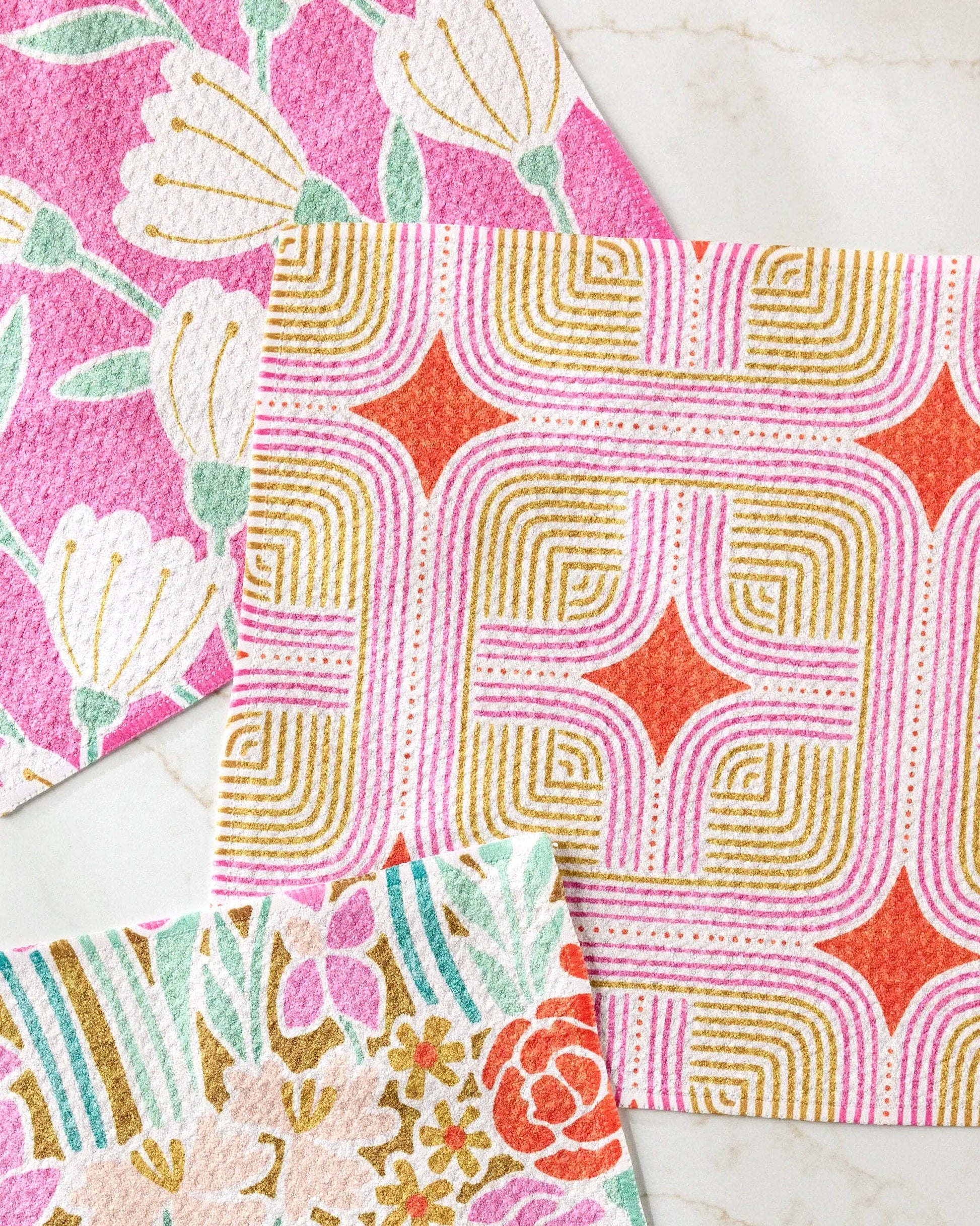 Colorful floral and geometric patterned dishcloths on a marble surface