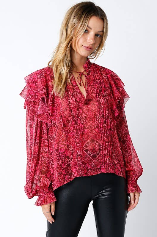Woman wearing a red floral ruffle blouse with long sleeves and black faux leather pants