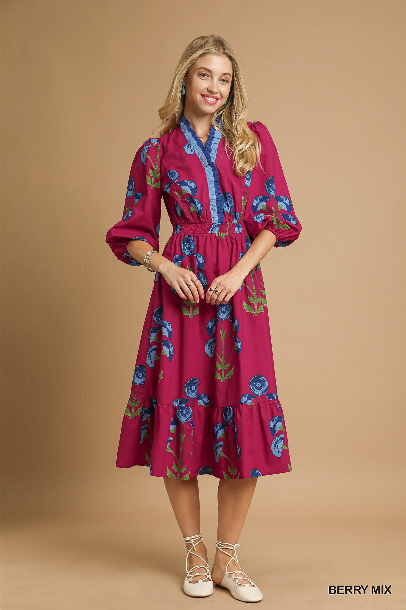 Model wearing a berry pink floral midi dress with blue trim neckline, puff sleeves, and tiered skirt — vibrant fall dress from Milo & Lily Boutique.