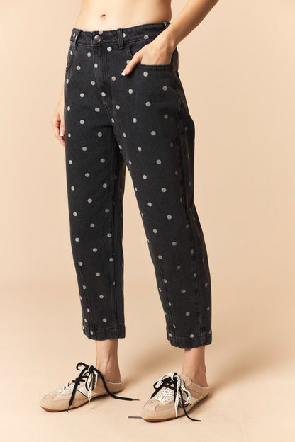 Person wearing black polka dot jeans on a beige background