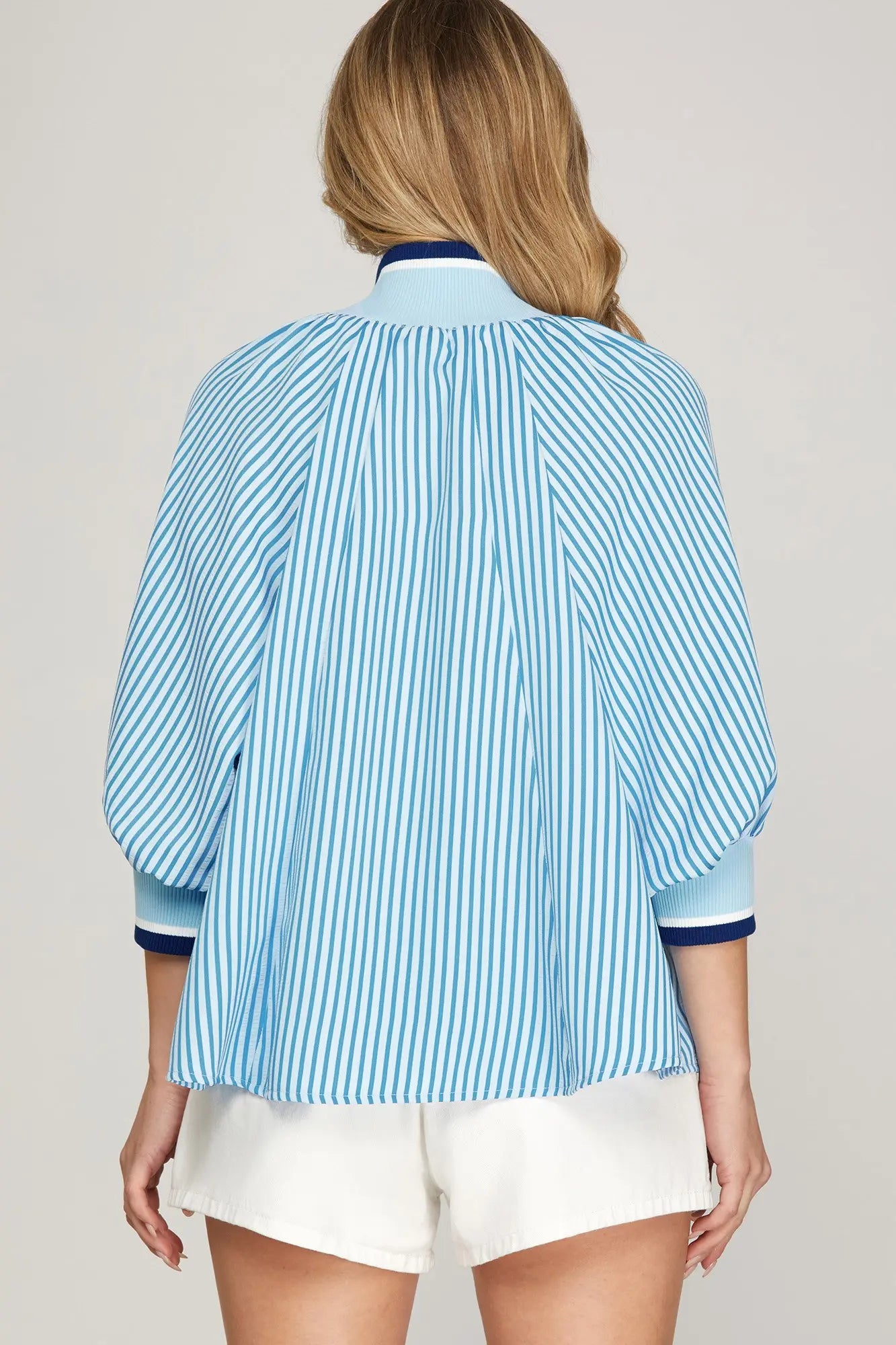 Woman wearing a blue and white striped shirt with a plain background