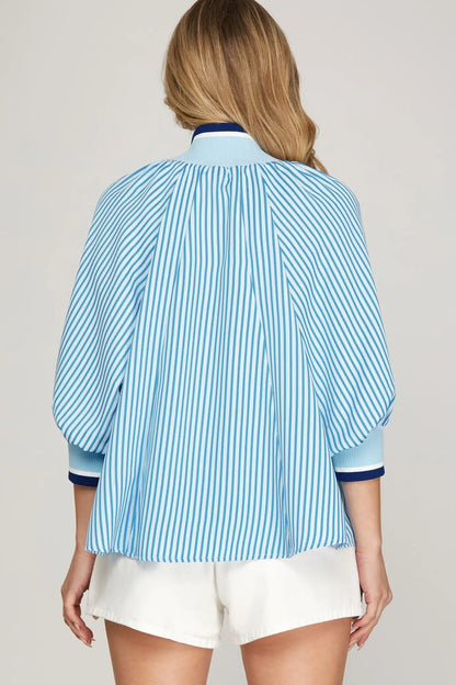 Woman wearing a blue and white striped shirt with a plain background