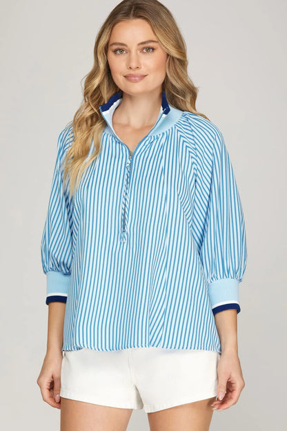 Woman wearing a blue striped zip-front blouse with quarter sleeves and white shorts