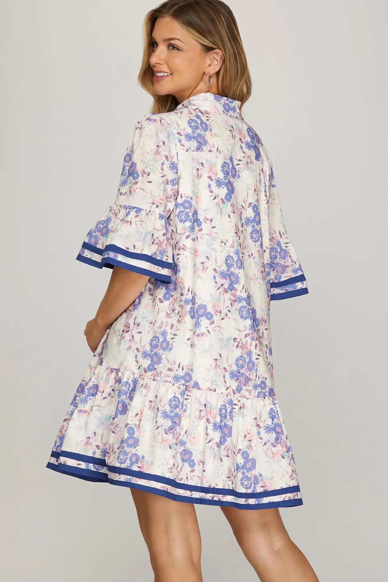 Woman wearing a floral dress with blue accents on a gray background