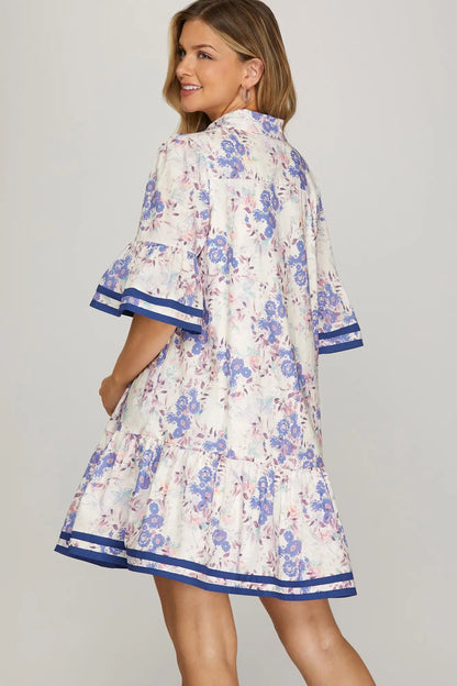 Woman wearing a floral dress with blue accents on a gray background