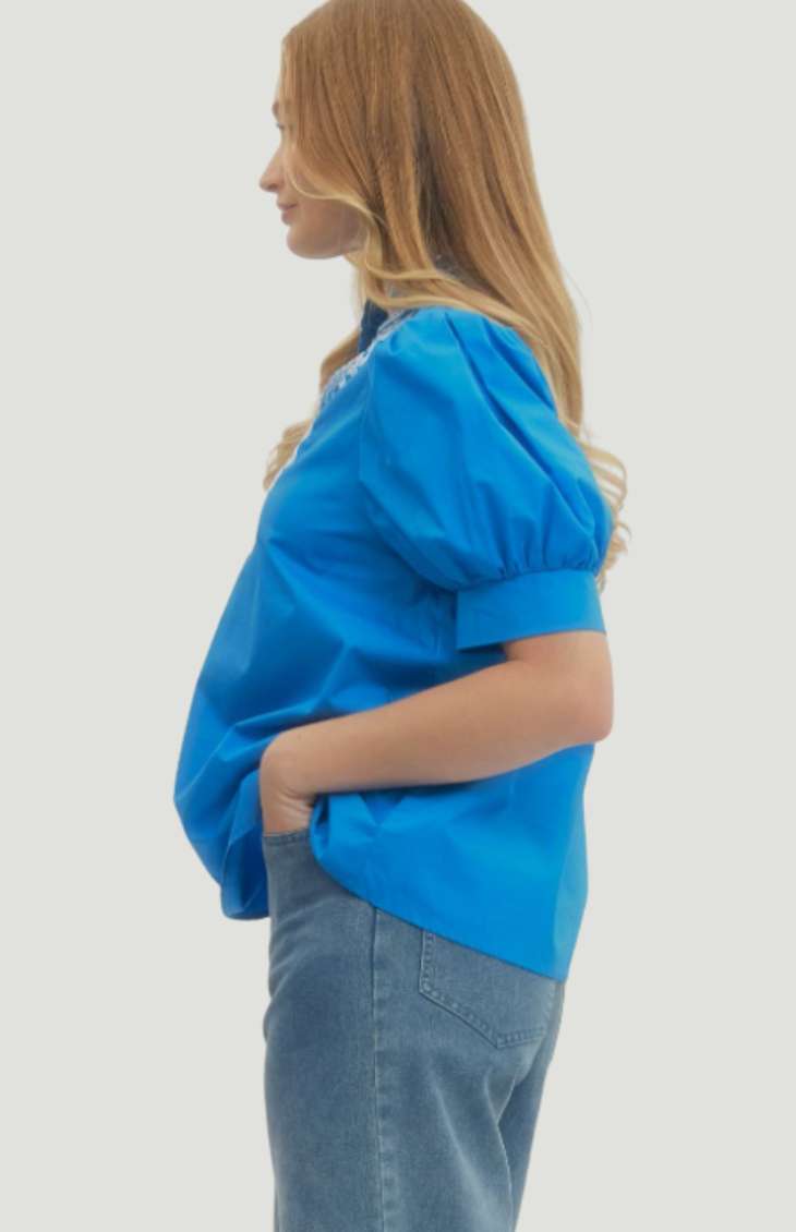 Side view of bright blue embroidered blouse with puff sleeves and relaxed silhouette, casual chic women’s top