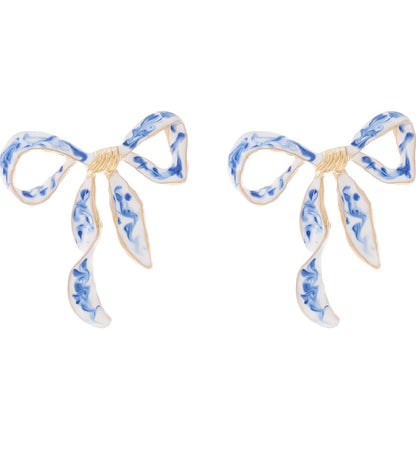 Blue and white enamel bow earrings with gold detailing, inspired by chinoiserie porcelain style — elegant and feminine accessory.