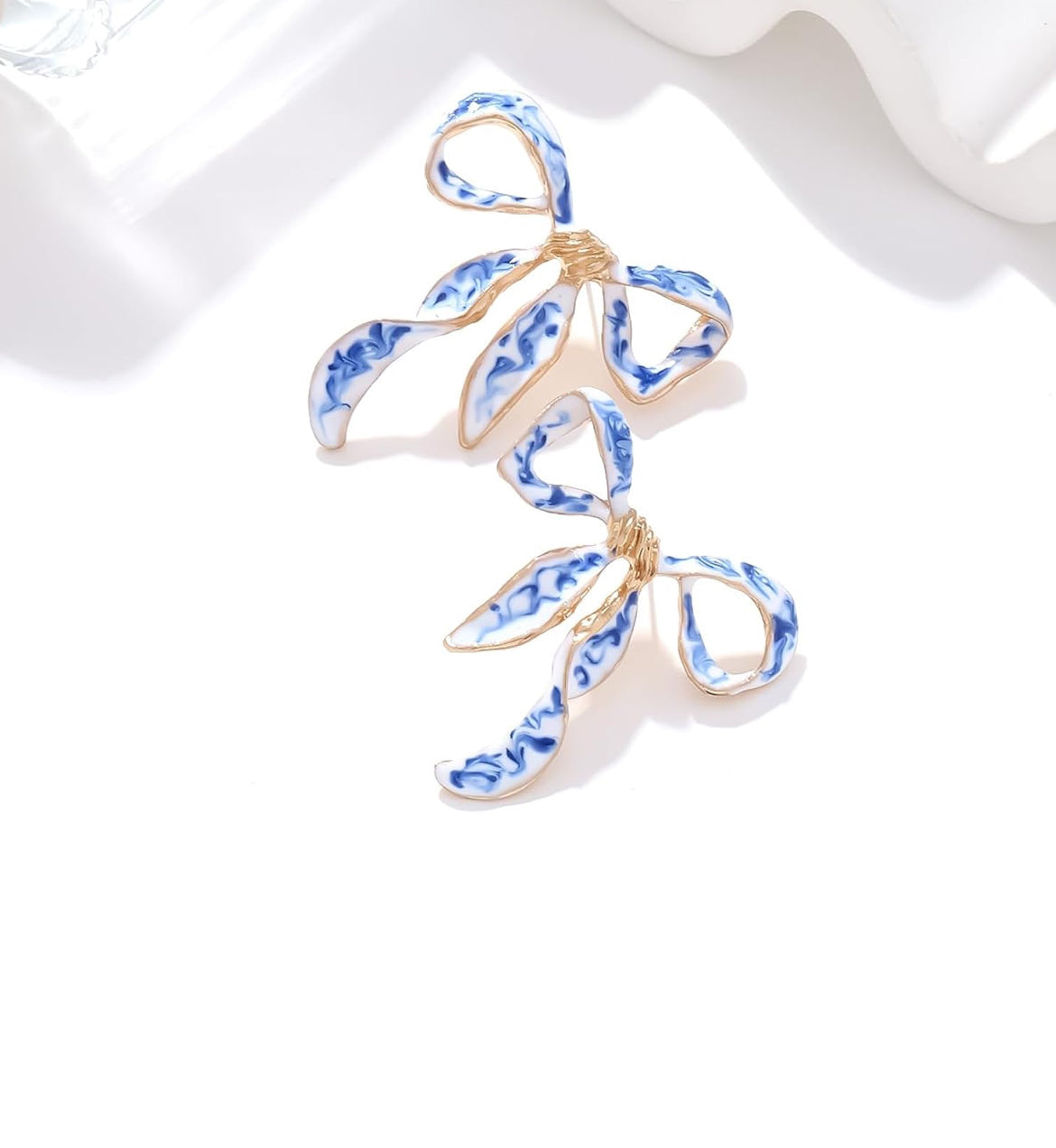 Blue and white enamel bow earrings with gold detailing, inspired by chinoiserie porcelain style — elegant and feminine accessory.