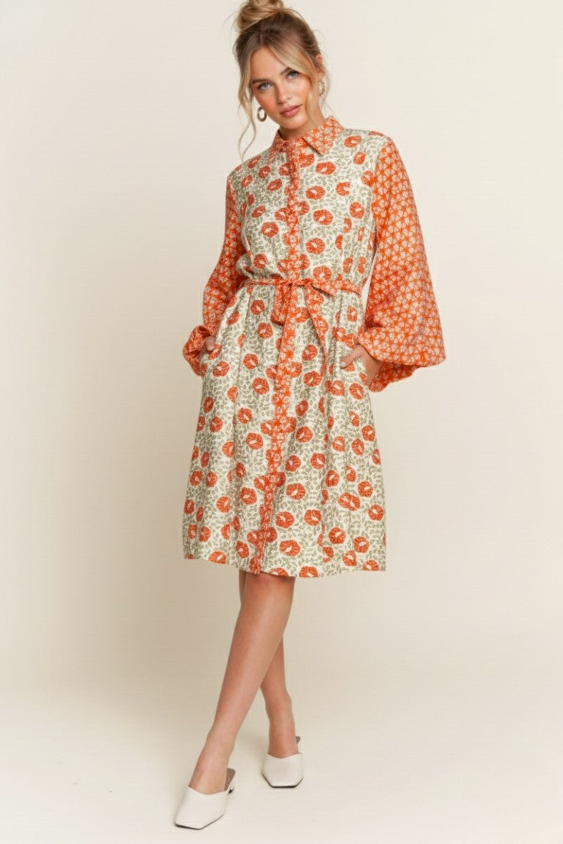 Woman wearing a floral dress with long sleeves on a plain background