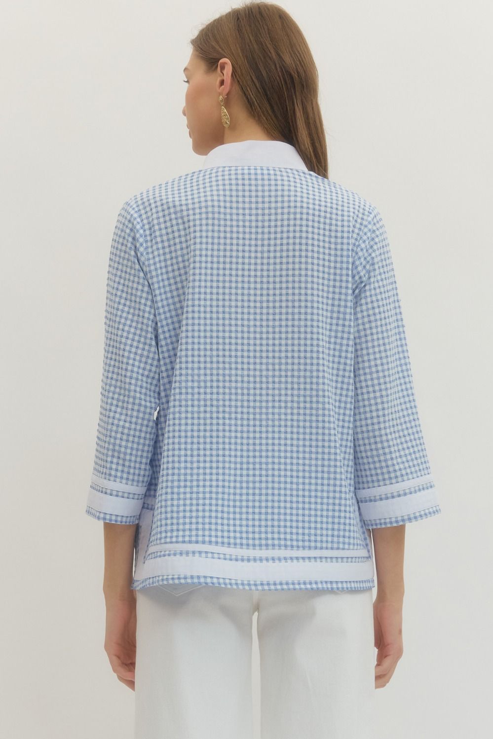 Woman wearing a light blue checkered shirt against a white background