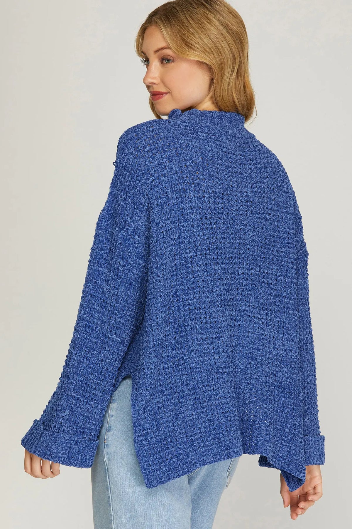 Woman wearing a blue textured sweater against a plain background